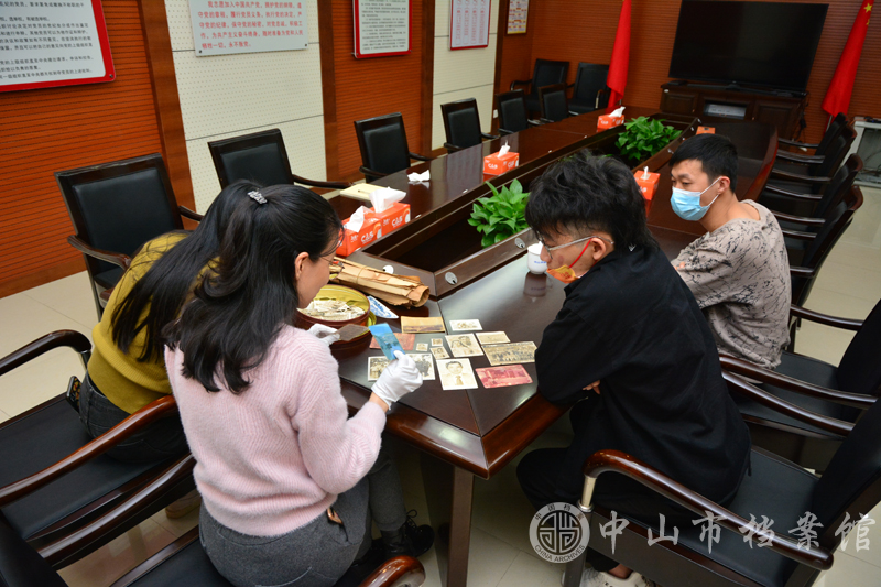 图4：郑辉豪先生(右二)向市档案馆工作人员介绍其捐赠的老照片（蓝子键 摄）副本.jpg